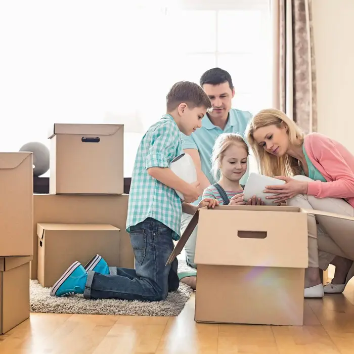 A family unpacking cardboard boxes in the living room of a UK home