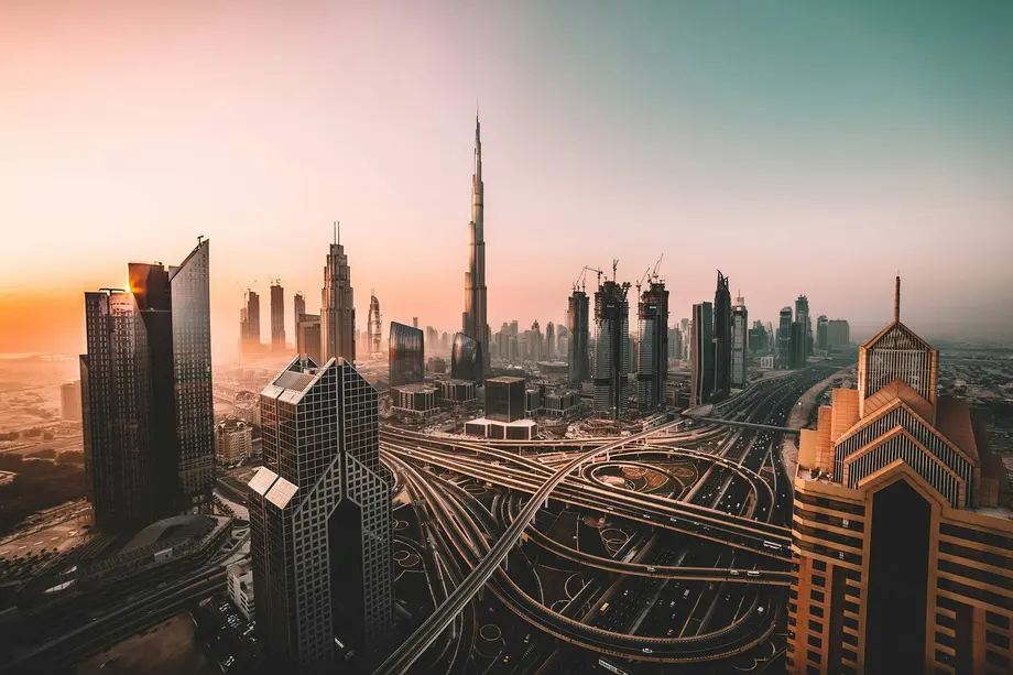 The Dubai skyline at sunrise, with the Burj Khalifa rising above the Sheikh Zayed Road interchange
