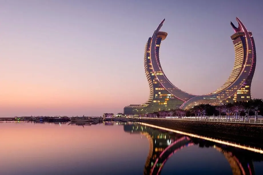 The crescent-shaped Katara Towers in Lusail, Qatar, reflected in the water at dusk
