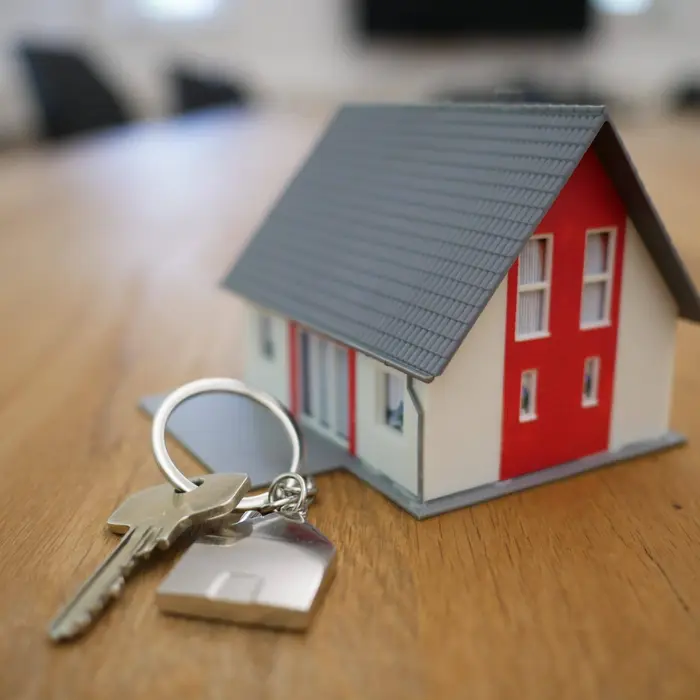 A model house and a set of door keys on a wooden table